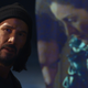 Neo standing in front of a screen with a Matrix movie playing on it.